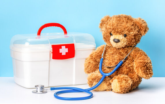 Pediatrician or family doctor concept. Teddy bear with stethoscope and first aid kit on a blue background