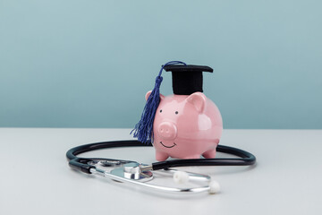 Pink piggy bank with stethoscope as a concept image of the costs of medical education