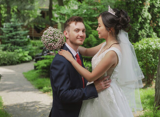 Portrait of an international loving couple of newlyweds against the backdrop of nature and flowers