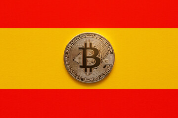 One bitcoin on a Spanish flag background. New regulations and laws for cryptocurrencies enters into...