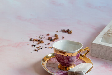 teapot and pink tea cup with tea bags and tea infuser ball