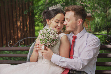 Portrait of an international loving couple of newlyweds against the backdrop of nature and flowers
