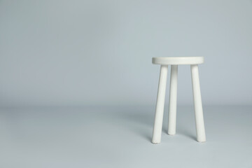 Stylish wooden stool on light grey background. Space for text