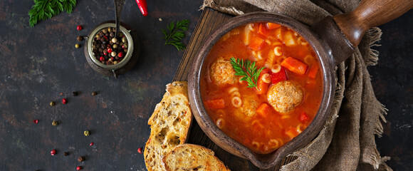 Spicy tomato soup with meatballs, pasta and vegetables.  Healthy dinner. Top view, banner