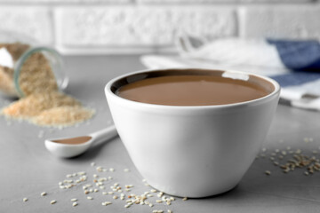 Tasty sesame paste in bowl on light grey table, closeup