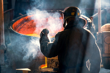 worker of metal and alloys foundry at a metallurgical plant, rear view
