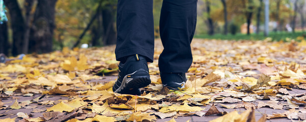 Man walks in autumn park. Top View of hiking Boot. Close-up Legs In J sport trekking shoes in the forest