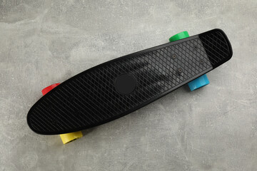 Black skateboard on grey stone background, top view. Sport equipment - Powered by Adobe
