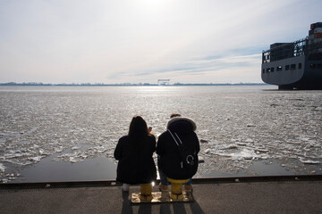 Two silhouettes of people from behind looking at the ice drift on the Elbe in Hamburg