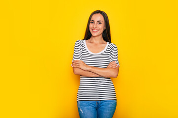 Beautiful smiling modern brunette woman in casual wear is posing against yellow wall