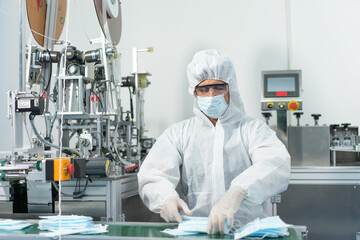 Male worker wearing personal protective equipment or PPE to protect and clean working in the hygienic mask production line at factory industry