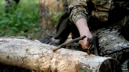 The tourist's hand takes an heavy ax to cut a branch. Tourism concept. Preparing firewood for the fire. Sunny day in the forest. The basics of survival.