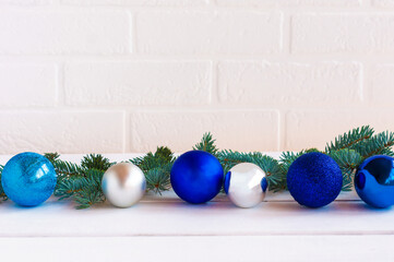Christmas composition with blue and silfer baubles and fir tree brances on white brick wall background with copy space for text