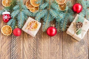 Frame with christmas background on old wood. Red and gold Baubles. Fir branches, dry oranges and cones. Xmas items. Top view.
