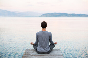 Young man practicing yoga and meditate near the sea at sunrise, Harmony, meditation, healthy...