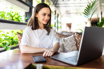 Young woman sitting at cafe with laptop