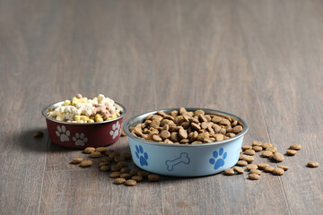 Bowls with dry dog food on wooden floor indoors