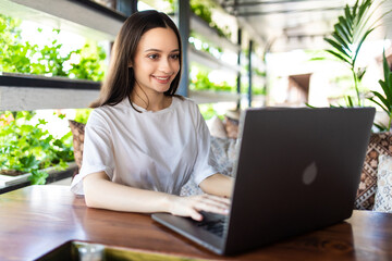 Young woman sitting at cafe with laptop