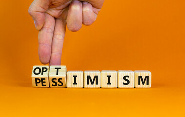Pessimism or optimism symbol. Businessman turns cubes and changes the word 'pessimism' to 'optimism'. Beautiful orange table, orange background. Business, optimism or pessimism concept. Copy space.