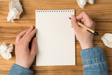 Above photo of notebook crushed paper hands with pen isolated on the wooden backdrop