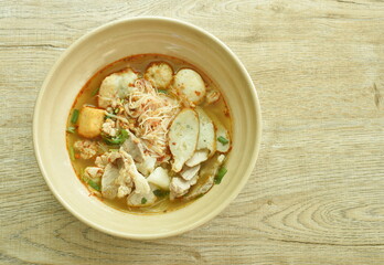 spicy vermicelli noodles topping slice boiled pork and ball in tom yum soup on bowl