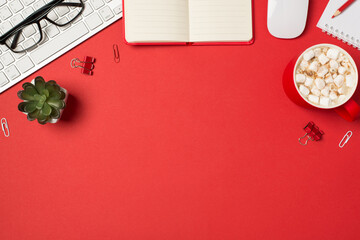 Top view photo of workspace keyboard glasses binder clips plant mouse pencil planners and cup of drink with marshmallow on isolated red background with copyspace