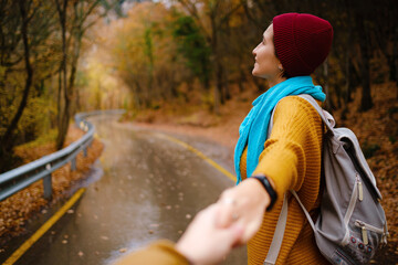 follow me concept woman in yellow sweater walking by road to forest
