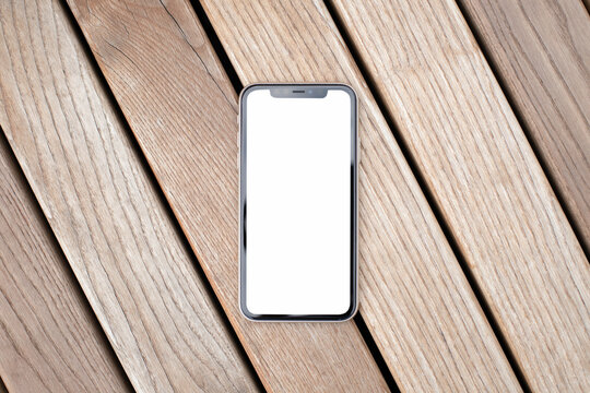 crop mockup image blank white screen cell phone. background empty space for advertise text. modern mobile phone lies on a wood bench ivory table
