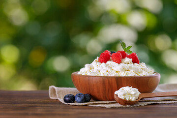 cottage cheese with fresh raspberry and blueberry on table outdoors