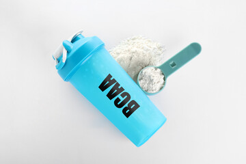 Shaker with abbreviation BCAA (Branched-chain amino acid) and powder on white background, flat lay
