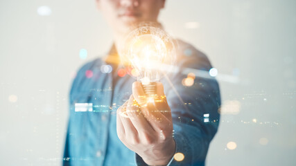 Innovation through ideas and inspiration ideas. Human hand holding light bulb to illuminate, idea of creativity and inspiration concept of sustainable business development. © Thapana_Studio