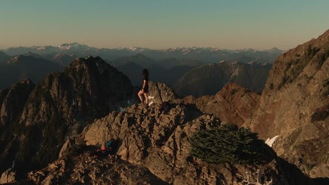 Adventurous Caucasian Woman Hiking on top of a Rocky Mountain Cliff. Sunny Summer Sunset. Mnt Brunswick Hike, North of Vancouver, British Columbia, Canada.