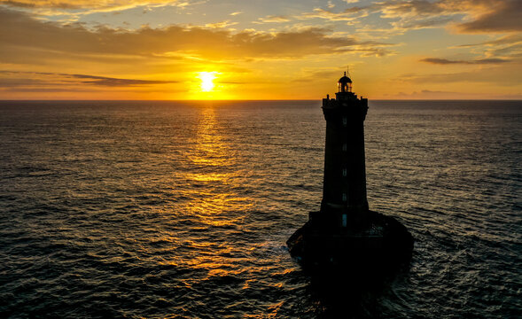 Luftaufnahme vom einzigartiger Sonnenuntergang &uuml;ber dem atlantischen Ozean vor der K&uuml;ste von Porspoder mit dem Leuchtturm der vier (Phare du Four), Bretagne, Frankreich