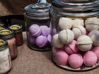 large glass jars filled with artisan made bath bombs in pastel colors on display table at farmer's...