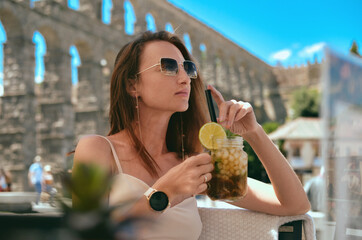 Woman sit in outdoor restaurant with mojito cocktail. Segovia. Spain