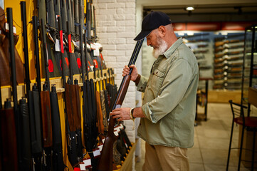 Hunter at showcase with hunting rifles, gun store