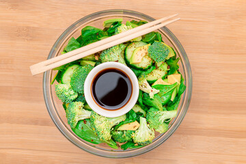 Fresh Green Salad of Avocado, Broccoli, Spinach and Cucumber for Detox with Soy Sauce on Wooden Cutting Board. Vegan Salad. Vegetarian Culture. Raw Food. Healthy Eating and Vegetable Diet