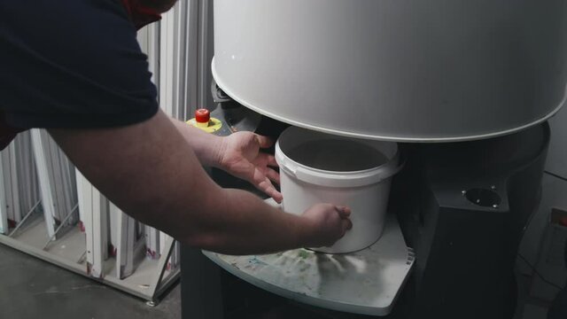 Slowmo shot of unrecognizable male hardware store worker putting bucket of paint into mixing machine