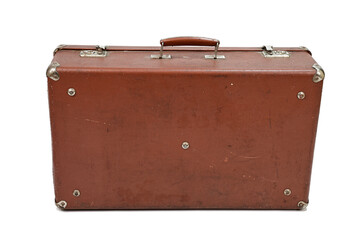 Old cardboard brown suitcase with metal corners and clasps. The suitcase is closed and stands with the handle up