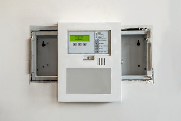 Retrofitted fire annunciator panel. Temporary installation of single-stage fire system replacement in small residential or commercial building. Old panel box opening still visible. Selective focus.