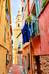 Fototapeta na wymiar Colorful street in the French Riviera town of Menton with basilica bell tower