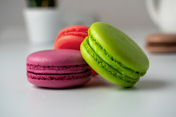 three macaroons on a white background. The back has a light blurred background. Side view. Delicious sweet dessert