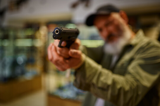 Bearded man aims a pistol in gun store