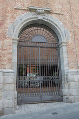 semicircular arched entrance with metal grille on a brick facade