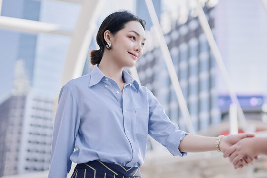 A beautiful Asian business woman is having a handshake with her client