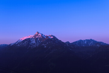 Fototapeta premium Pink sunrise or sunset on mountain. Beautiful landscape with clear sky over the summit of a valley in alps.