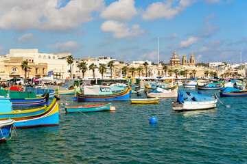 Fototapeta na wymiar Traditional Luzzu fishing boats moored at Marsaxlokk harbor, Malta
