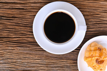 black coffee in white seramic glasses and almond caramel croissant  on  wooden table