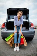 Woman with bags at the opened trunk on parking