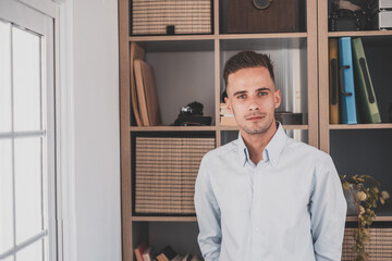  Portrait of one young cheerful male smiling having fun at home. Attractive young caucasian man studying independent looking at the camera and posing to picture.
